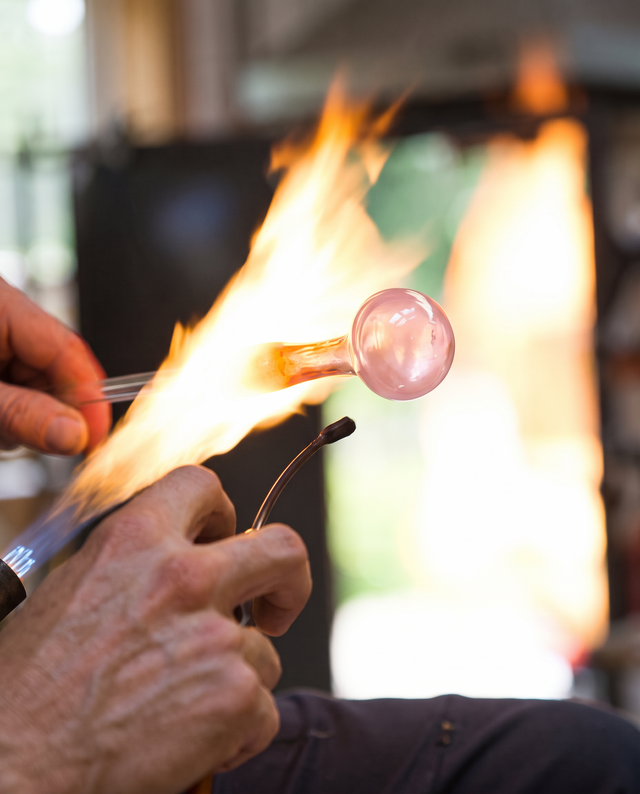 Glassblower shaping a hand pipe in the torch flame
